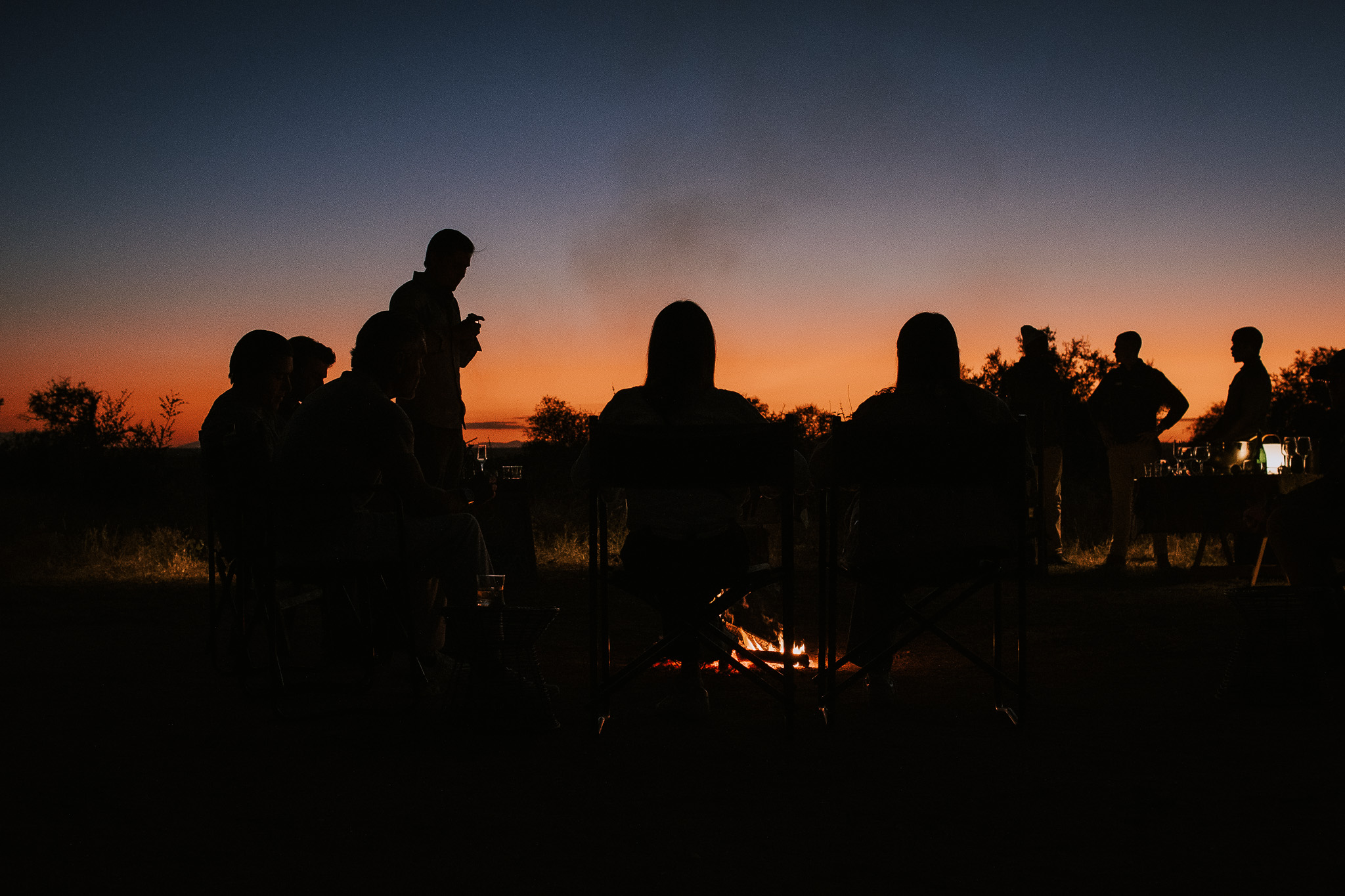 sitting around the fire watching the sunset on safari