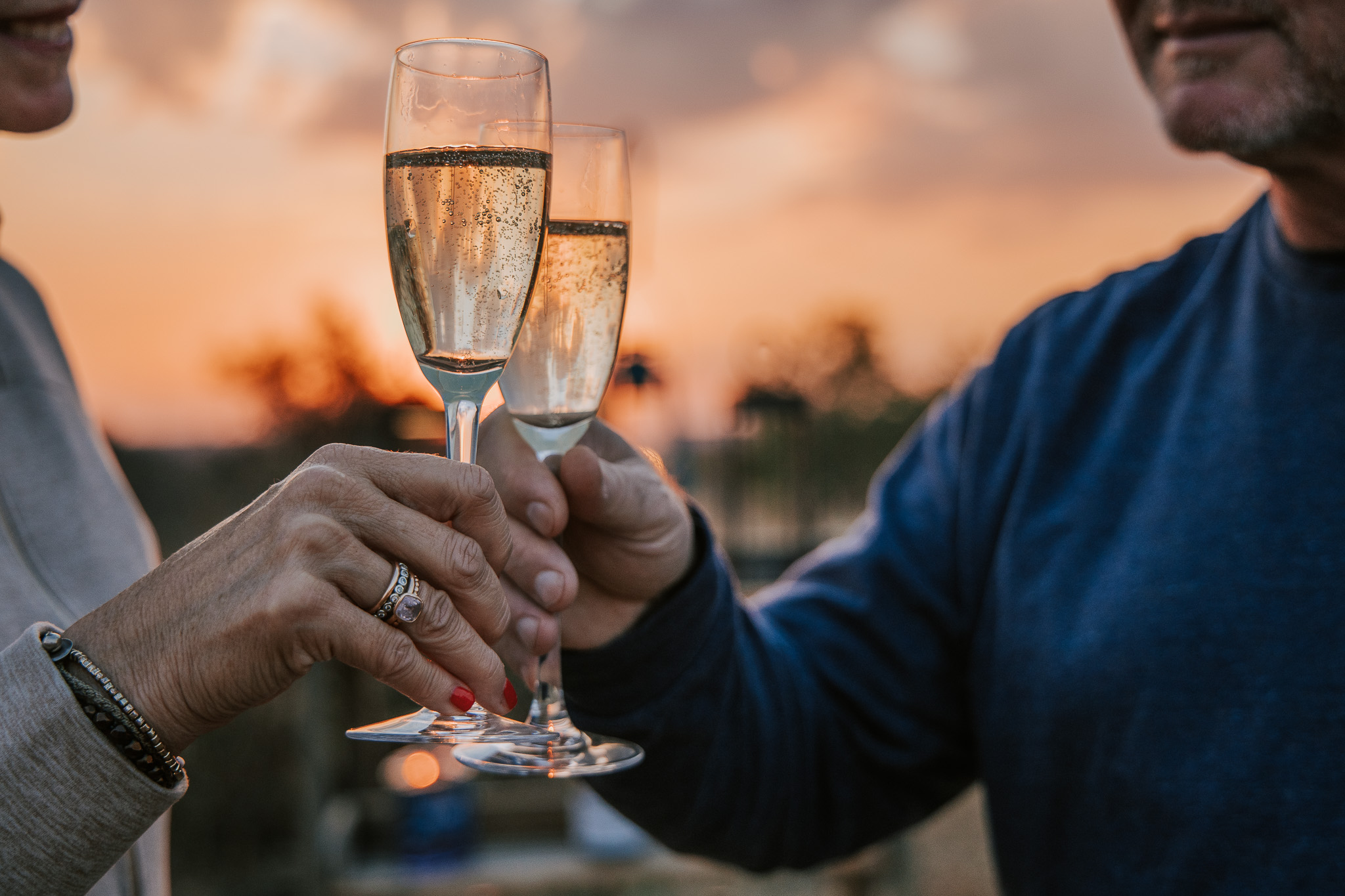 Couple toasting champagne glasses at sunset on safari.