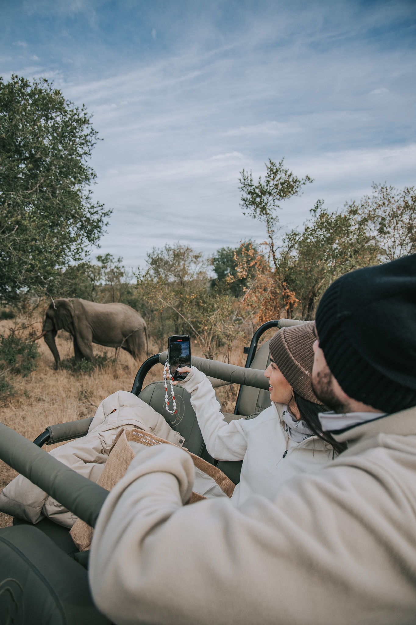 Couple on safari capturing photos of an elephant from a game vehicle.