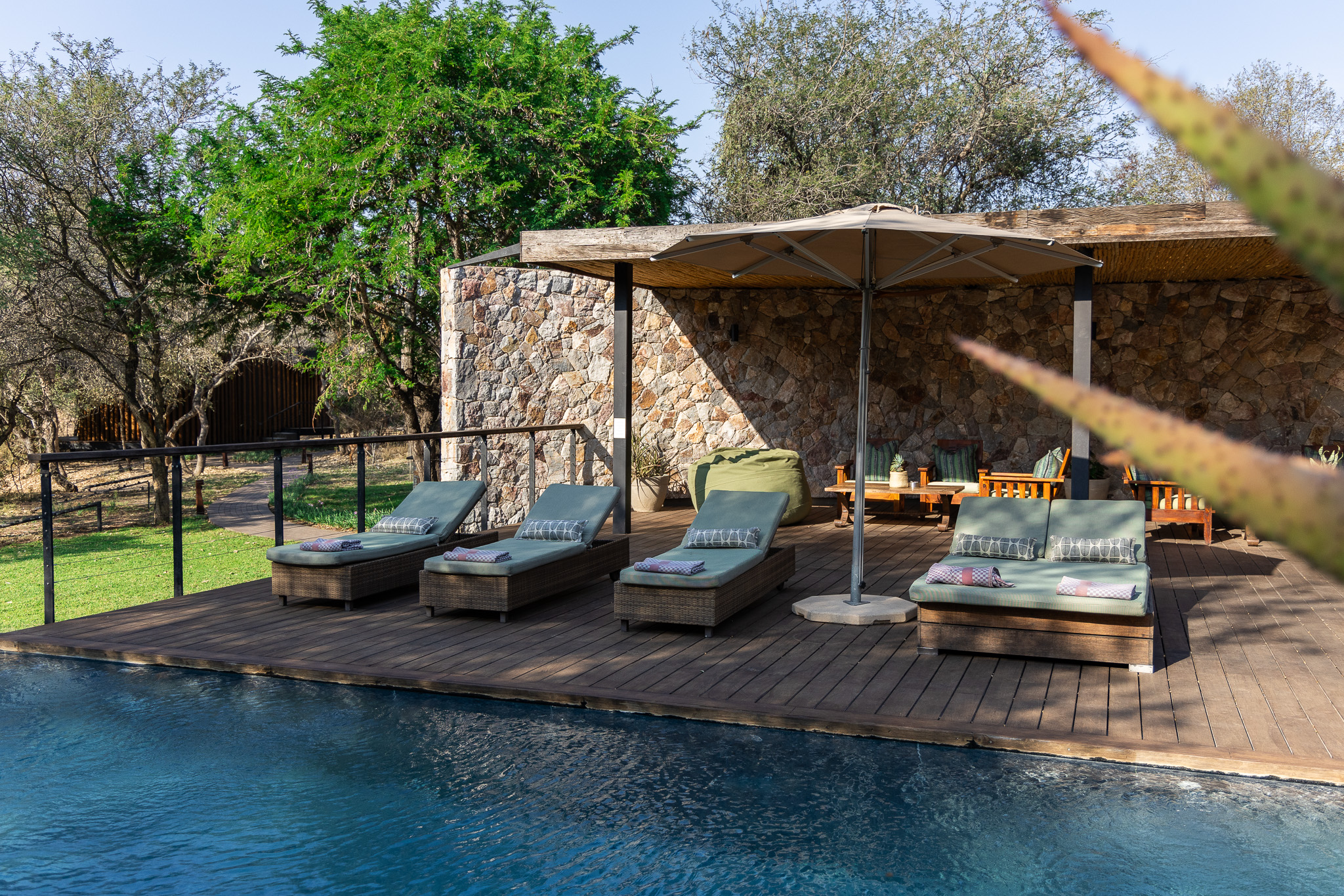 Guest sun loungers beside the pool at Tanda Tula Safari Camp on a warm spring day.