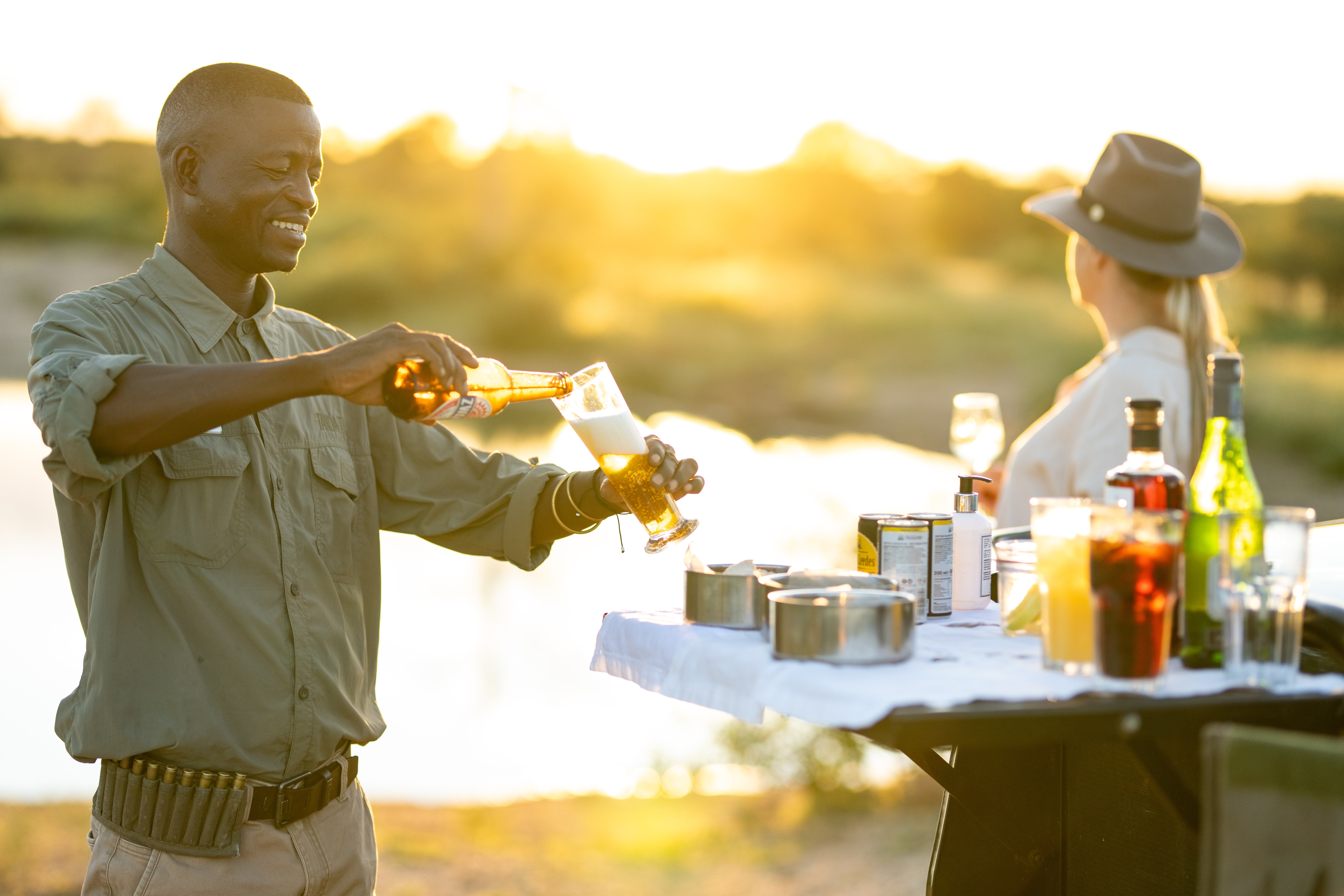 Guests enjoying drinks around a lantern-lit fire at dusk in the Timbavati.