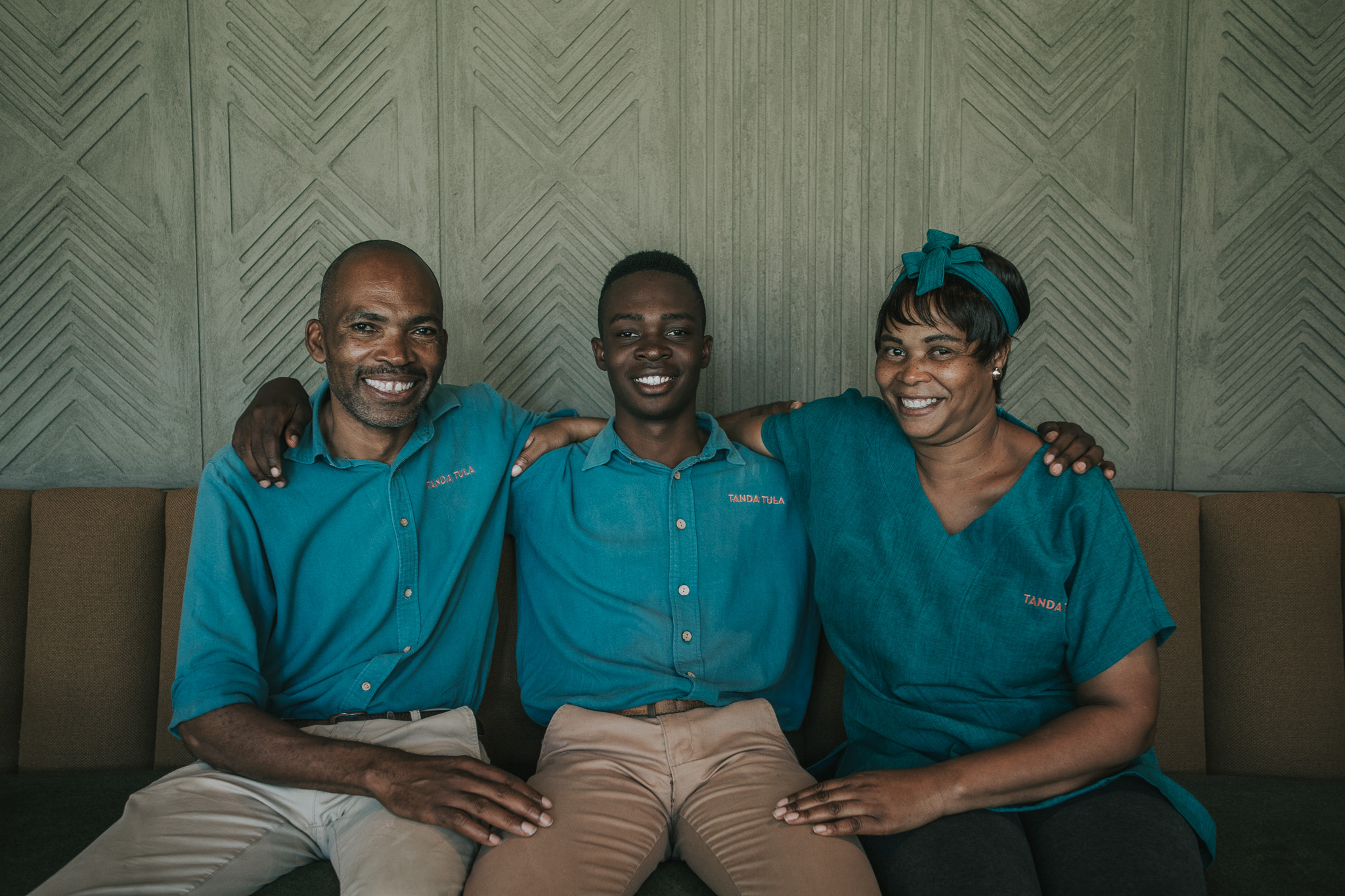 Three Tanda Tula team members smiling together in the camp lounge, symbolising the family spirit of the lodge.
