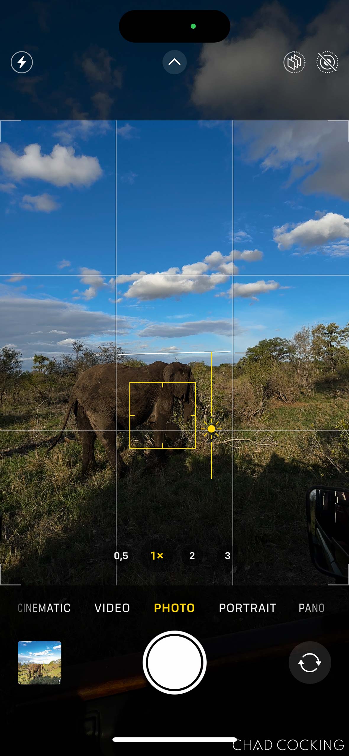 iPhone camera screen showing the exposure slider being moved downward to darken the image.