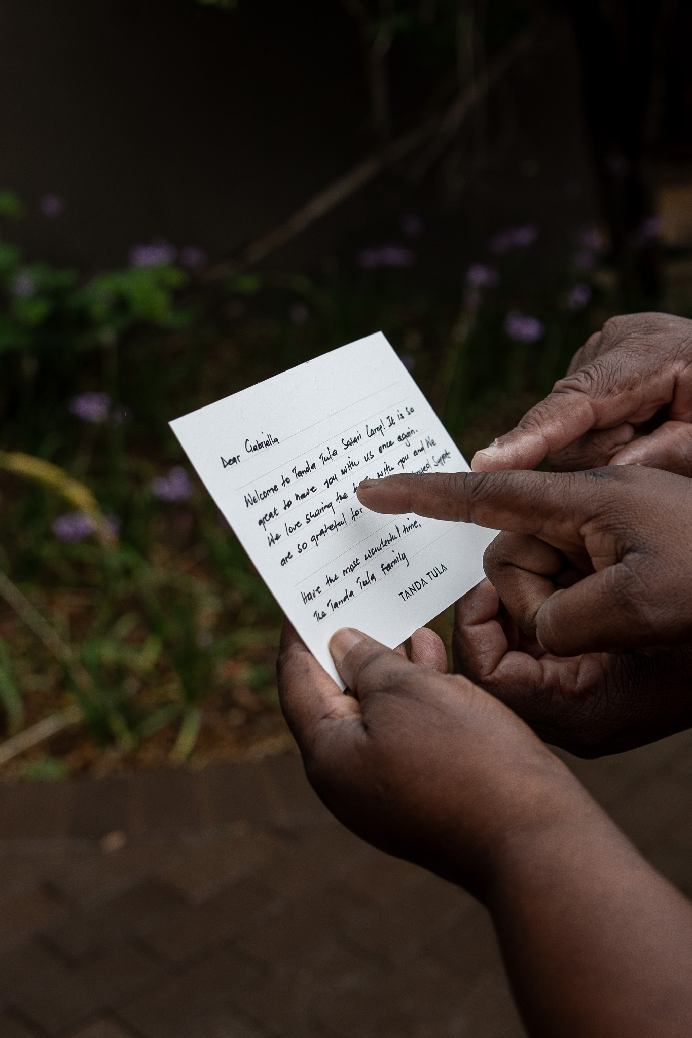 Close-up of two Tanda Tula team members reading a handwritten guest welcome card together.